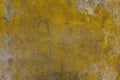 Old dirty yellow concrete wall with cracks, scratches, peeling gray and white paint and dark mold stains. rough surface texture Royalty Free Stock Photo