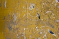 Old dirty yellow concrete wall with damages, gray stains of paint and remnants of torn paper ads. rough surface texture Royalty Free Stock Photo