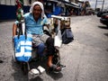 An old disabled man rolls around in his wheelchair in a public market.