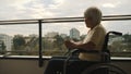 Old disabled woman in wheelchair on the terrace drinking a cup of tea or coffee. Royalty Free Stock Photo