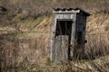 Old disintegrating wooden booth with torn door in grass