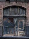 Old distressed wooden doors on brick factory building with peeling paint Royalty Free Stock Photo