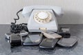 Old disused landline telephone set of gray color and old mobile phones nearby close-up