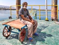 Old docker sits on handcart in the port, South Iran. Royalty Free Stock Photo