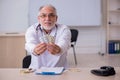 Old male doctor suggesting pills in the clinic