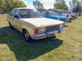 Old Dodge 1500 sedan 1970s in the countryside. Nature, grass, trees. Classic economy car.