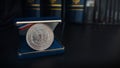 Old 1 dollar silver coin on a black table with binders and books in the background Royalty Free Stock Photo
