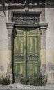 Old door in Cyprus with peeling green paint and overgrown by weeds Royalty Free Stock Photo