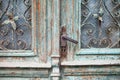 Old door handle close up. Metal handle and door lock of an old wooden door. Vintage green wooden door with metal lattice Royalty Free Stock Photo