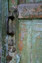 Old door with peeled paint and vintage big metal handle, green and orange vintage background, wooden door close up Royalty Free Stock Photo