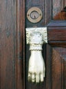 Old doorknocker in the shape of a hand and brass keyhole