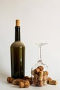 Old dust wine bottle, upturned wine glass and corks on white