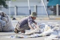 Old dustman picking up garbage in the harbor