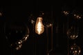 old dusty incandescent lamp bulb on the wire shines in the dark and mirror balls around