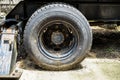 Old dusty tractor car wheel with rusty steel drum and knots attached to black frame stand