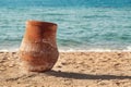Old earthen pitcher standing on the sand near the sea Royalty Free Stock Photo