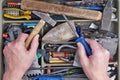 The old elderly repairman examines rusty tools in his dirty ru