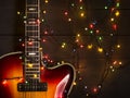 Old electric guitar with a lighted garland on a dark background. Greeting, Christmas, New Year greeting card. Copy space. Royalty Free Stock Photo