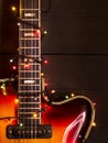 Old electric guitar with a lighted garland on a dark background. Greeting, Christmas, New Year greeting card. Copy space. Royalty Free Stock Photo