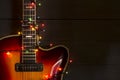 Old electric guitar with a lighted garland on a dark background. Greeting, Christmas, New Year greeting card. Copy space. Royalty Free Stock Photo