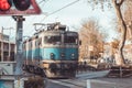 Old electric locomotive passing the grade crossing in the centre of Rijeka on a sunny winter day. Bells ringing and flashing