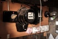 Old electric meter for calculating energy consumption is hanging in the barn, next to sockets and a light bulb. Russia.