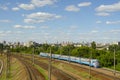 An old electric train moves on rails in the summer season against the backdrop of a cityscape and skyscrapers under construction Royalty Free Stock Photo