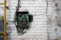 Old electrical panel on the wall of the house. Electric cables stick out from the electric panel on the white brick wall of the Royalty Free Stock Photo