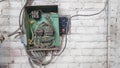 Old electrical panel on the wall of the house. Electric cables stick out from the electric panel on the white brick wall of the Royalty Free Stock Photo