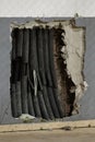 Old electrical wires in damaged plastic insulation, in mounting hole in the wall. Dangerous and bad electrical wiring,