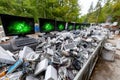 Old electronic equipment is piled in a recycling yard surrounded by trees during daylight Royalty Free Stock Photo