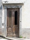 Old elegant weathered ornate wooden brown door with carved panels and missing grille in a white abandoned house