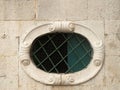 Old elliptical window with metal grill on stone facade in Montenegro Royalty Free Stock Photo