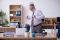 Old male employee suffering from radiculitis at workplace