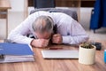 Old male employee suffering from radiculitis at workplace