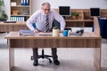 Old male employee suffering from radiculitis at workplace