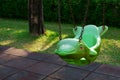 Green hanging swing in dolphin shape and rubber floor tiles in playground of public park