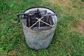 Old empty honey extractor centrifuge on green grass