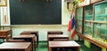 Old empty vintage classroom with old wooden desk, chair, cabinet with Thailand flag and blackboard Royalty Free Stock Photo