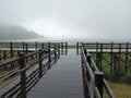 Old empty wooden bridge with gray sky over the lake on an rainy day with fog Royalty Free Stock Photo