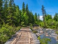 Old empty wooden bridge over a mountain river on the background of coniferous forest and mountains Royalty Free Stock Photo