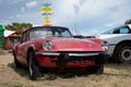 Old English compact sports car parked on the grass, it's a red Triumph Spitfire