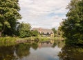 Old english historic cottage seen over a lake with reflections Royalty Free Stock Photo