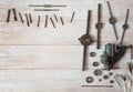 Locksmith vises, dies and taps of different diameters, a pipe wrench and work gloves on a wooden background.