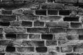 Old eroded brick wall with knocked out bricks. ?rumbling brick wall. Black and white photo