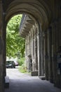 Old European courtyard with wooden balconies. View through a stone arch to green trees. Departure from the yard. Budapest. Hungary