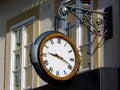 old European facade detail with large suspended wall clock on steel bracket