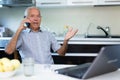 Old man with laptop talking on phone Royalty Free Stock Photo