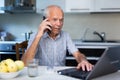 Old man with laptop talking on phone Royalty Free Stock Photo