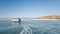 An old excursion off-road bus rides on the ice of the frozen lake Baikal in Siberia. The bright winter journey through Russia.